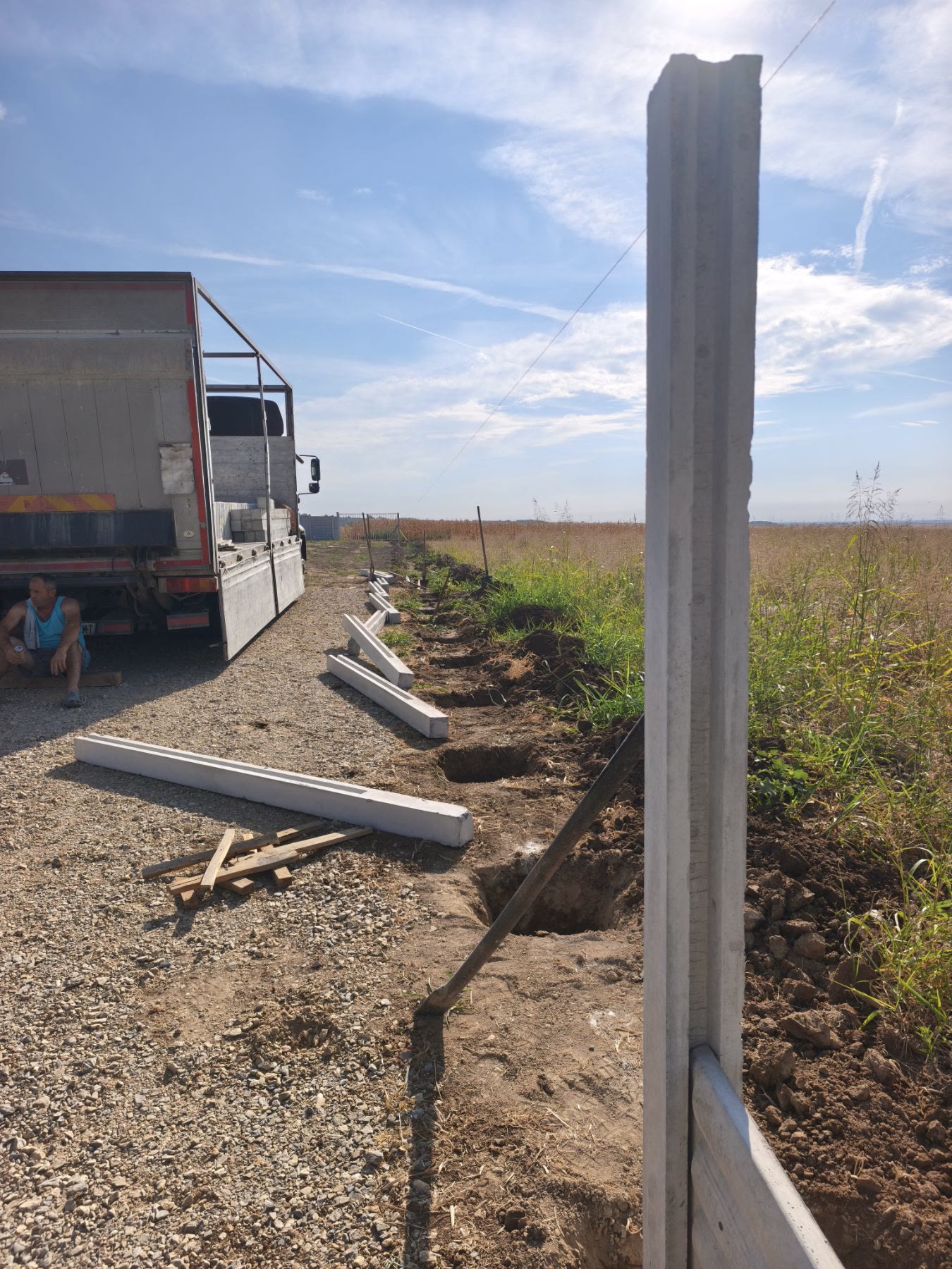 Betonski stubovi poređani uz liniju ograde pored iskopanih rupa, Ruma